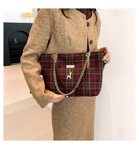 Close-up of wool plaid handbag with gold chain strap and deer charm on model