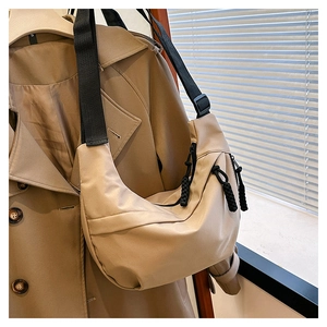 Detail of khaki nylon crescent bag with black adjustable strap and woven zipper pull