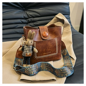Detail of dark brown leather bucket bag with wide ethnic strap and cute rabbit pendant