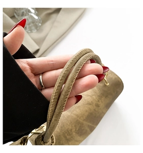 Close-up of the woven handle detail and textured leather on a chic square handbag