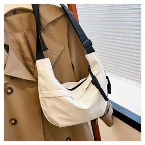Detailed view of white nylon crescent bag with woven knot zipper and adjustable strap