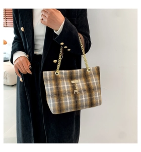 Detail of plaid tweed tote bag featuring gold chain strap and deer charm pendant