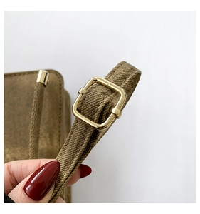 Macro shot of brown textured shoulder strap with polished gold rectangular buckle