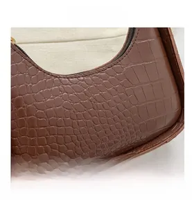 Detailed close-up of dark brown crocodile embossed leather texture with gold zipper