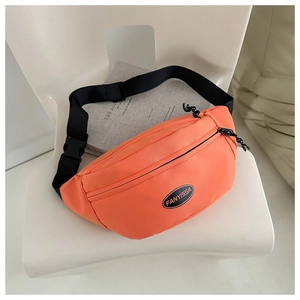 Detail of bright orange nylon waist bag with black adjustable strap and buckle on white chair