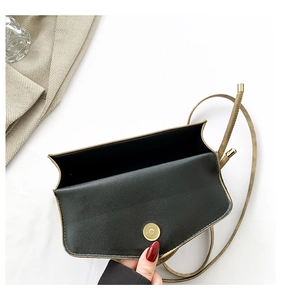 Detail of black mini crossbody bag featuring a golden cylindrical magnetic closure and lining