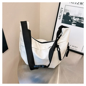 Detailed shot of white crescent crossbody bag featuring black nylon strap and dual zippers