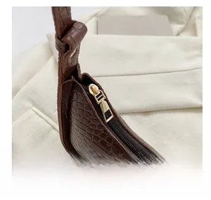 Detail of dark brown crocodile-patterned leather with a premium gold zipper fastener