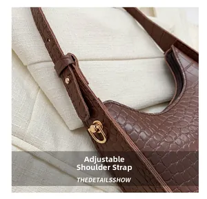 Detail of adjustable shoulder strap and gold buckle on dark brown crocodile pattern bag