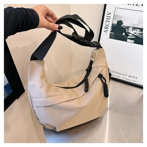 Detail of beige nylon dumpling bag with adjustable strap and double zipper pulls
