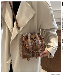 Model view of a vintage plaid wool bucket bag with a leather woven handle and drawstring