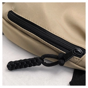 Detailed macro view of khaki nylon bag with black zipper and woven paracord pull cord