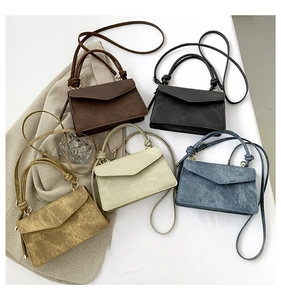 Flat lay of small crossbody bags in five colors with unique knotted handles and V-shaped flaps