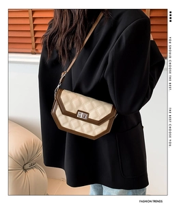 Detail of quilted crossbody bag with turn-lock closure and contrast leather piping