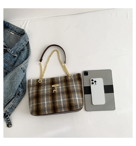 Detail of tweed tote bag with gold deer charm, chain strap, and daily essentials