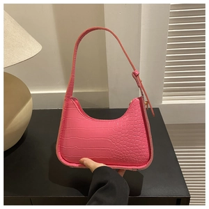 Dettaglio della trama a coccodrillo rosa acceso e cerniera sulla borsa baguette