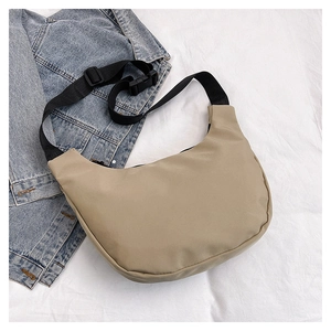 Detail of khaki nylon crescent bag with adjustable strap on denim jacket background