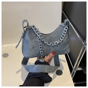 Detail of grey-blue washed denim half-moon bag featuring a thick silver metal chain strap