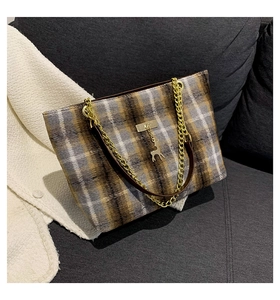 Detail of autumn tweed tote bag featuring a golden deer charm and metal chain strap