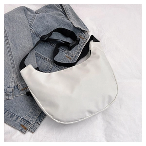 Detail of white nylon hobo bag with a wide adjustable black strap on denim jacket