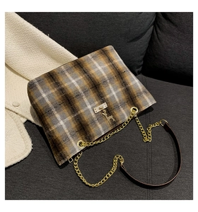 Close-up of vintage plaid wool handbag with golden chain strap and deer pendant detail