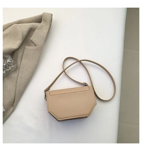 Detail view of beige quilted leather crossbody bag on a grey herringbone suit blazer
