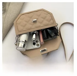 Detail view of beige quilted crossbody bag showing internal space for phone and makeup