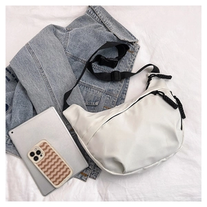 Detail of white nylon dumpling bag with black strap and buckle on lifestyle flat lay