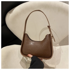 Dettaglio della trama coccodrillo marrone scuro sulla borsa hobo a mezzaluna piccola