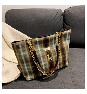 Detail of vintage plaid wool tote bag featuring a gold deer charm and chain strap