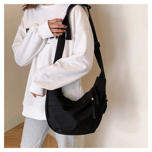 Detail of adjustable wide shoulder strap on black nylon crescent crossbody bag