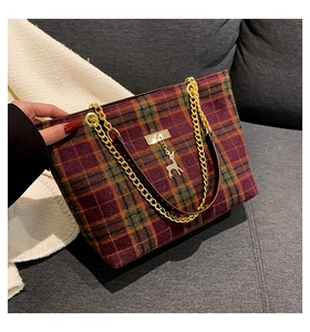 Detail of red and green plaid wool tote bag with gold chain strap and elk charm accent
