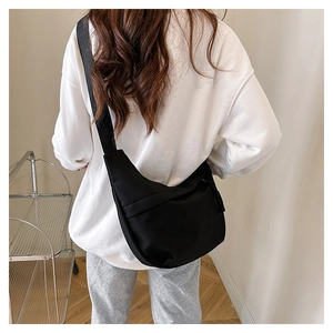 Rear view of a black nylon crescent crossbody bag worn with casual sports attire