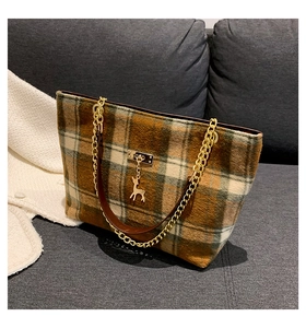 Detailed view of the gold deer pendant and plaid wool texture on the shoulder bag