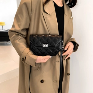 Close-up of black quilted leather crossbody bag with silver twist lock on a trench coat