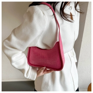 Dettaglio della trama a coccodrillo rosa acceso e della zip sulla borsa baguette