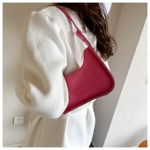 Primo piano della borsa hobo fucsia con stampa coccodrillo portata a spalla