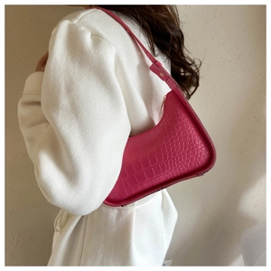 Borsa a spalla rosa con trama coccodrillo indossata dalla modella a forma di mezzaluna