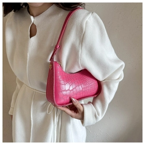 Detail of bright pink crocodile embossed hobo bag with gold hardware and leather strap