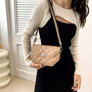 Beige quilted crossbody bag with silver twist lock shown on a model in a stylish outfit