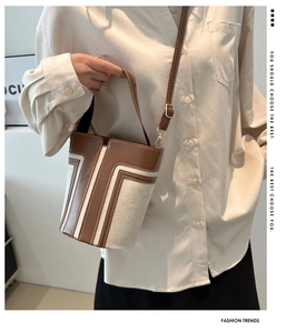 Dettaglio della borsa a secchiello vintage con pelle marrone, tessuto beige e design a T