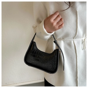 Dettaglio della trama a coccodrillo nera di una borsa hobo indossata da una modella