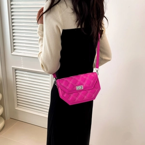 Close-up of bright pink quilted crossbody bag with silver twist lock and fine stitching