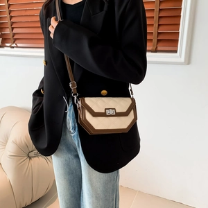 Detail of beige quilted crossbody bag with silver twist lock and dark brown trim accents