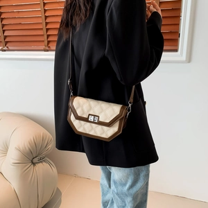 Quilted crossbody bag with metallic clasp worn by a model in a warm interior setting