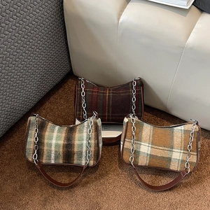 Three retro British plaid underarm bags with chain straps in earthy tones on a sofa