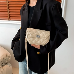 Detail of cream quilted crossbody bag with silver twist lock and modern angular shape