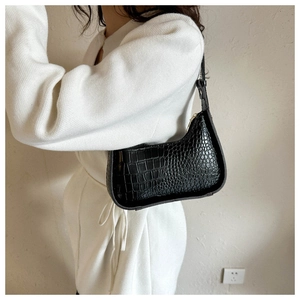 Detail of black crocodile pattern underarm bag with gold zipper and adjustable strap