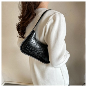 Detail of black crocodile embossed leather shoulder bag on a minimalist model shoulder