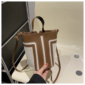 Dettaglio della borsa a secchiello in pelle marrone e tela con cuciture e hardware oro